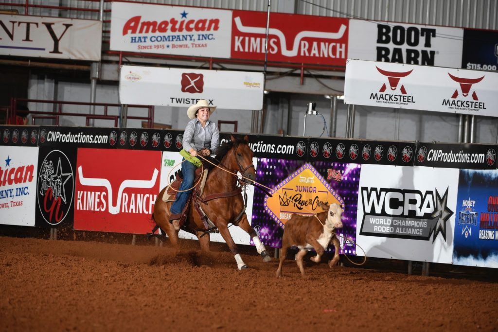 Cowgirl in rodeo arena executing breakaway roping on calf.